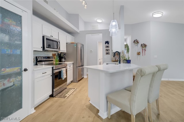 kitchen with white cabinetry, light hardwood / wood-style floors, decorative light fixtures, a kitchen bar, and appliances with stainless steel finishes