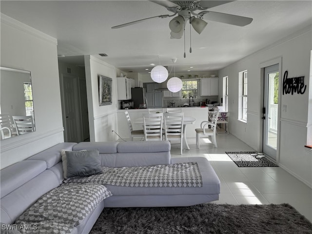 tiled living room with crown molding and ceiling fan