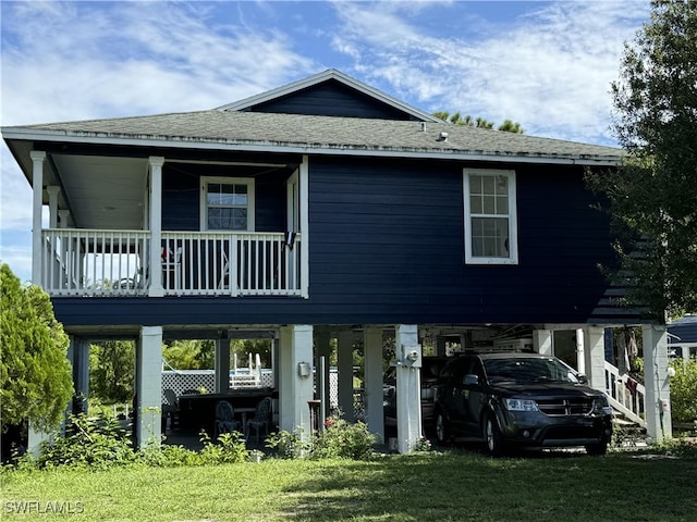 view of front facade with covered porch, a carport, and a front lawn