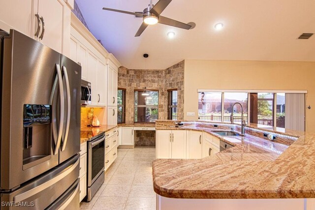 kitchen with a large island, sink, light stone counters, white cabinets, and appliances with stainless steel finishes