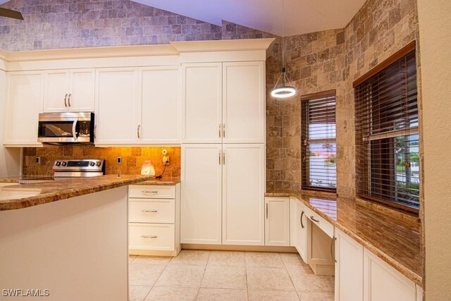 kitchen with stainless steel appliances, vaulted ceiling, pendant lighting, stone counters, and light tile patterned flooring