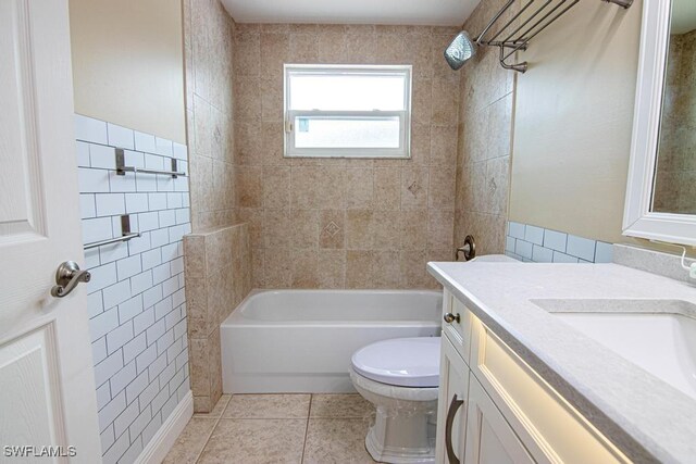 full bathroom with tiled shower / bath combo, tile patterned floors, toilet, vanity, and tile walls