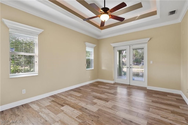 spare room with a raised ceiling, french doors, and light hardwood / wood-style floors