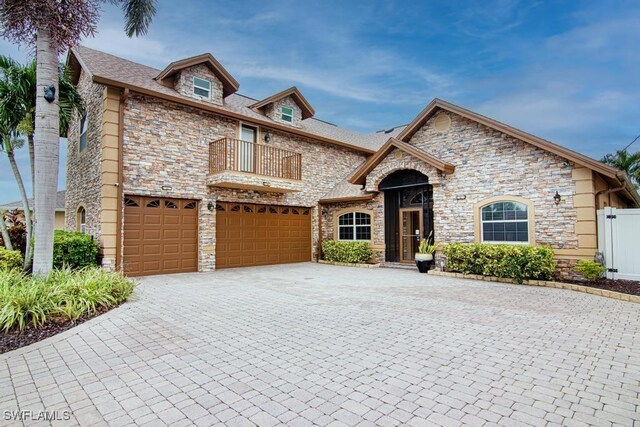 1201 SW 13th St, Cape Coral, FL 33991 - view of front of house with stone siding, a balcony, decorative driveway, and a garage