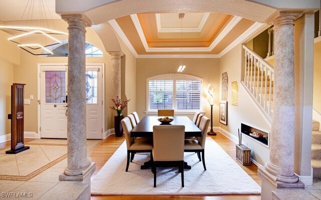 dining room with ornate columns, crown molding, and light hardwood / wood-style flooring