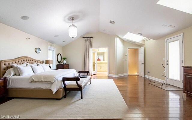 bedroom with hardwood / wood-style floors, vaulted ceiling, and ensuite bath