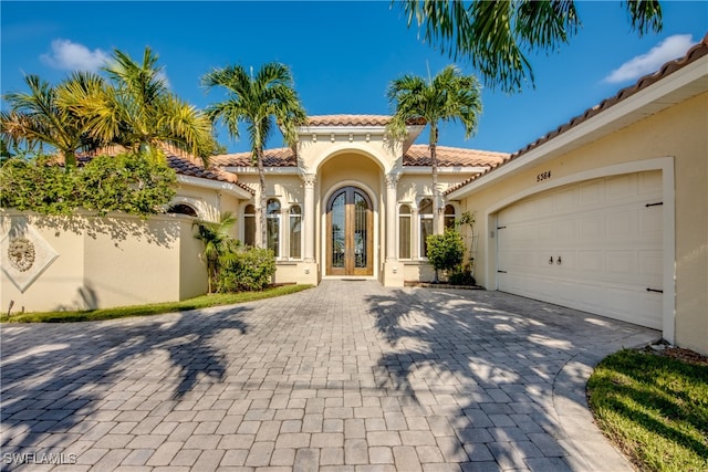 mediterranean / spanish-style house with french doors, decorative driveway, a tile roof, and stucco siding