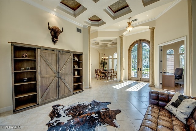 entrance foyer featuring crown molding, coffered ceiling, a high ceiling, and ornate columns