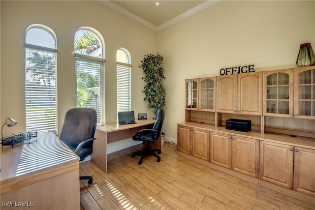 home office featuring crown molding, built in desk, and light hardwood / wood-style flooring