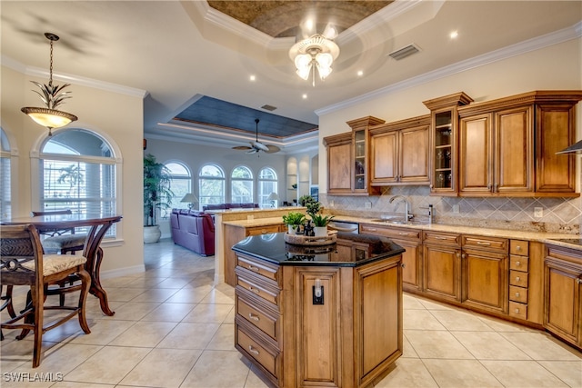 kitchen featuring a healthy amount of sunlight, ceiling fan with notable chandelier, and a tray ceiling