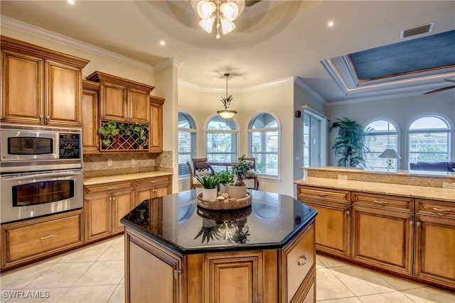 kitchen with a wealth of natural light, a kitchen island, ceiling fan with notable chandelier, and appliances with stainless steel finishes