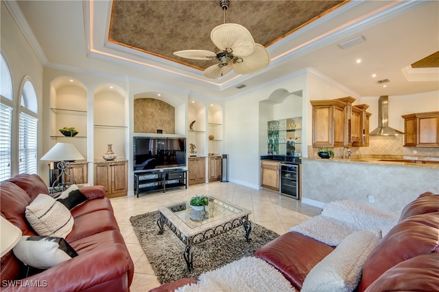 tiled living room featuring built in shelves, crown molding, a raised ceiling, and wine cooler