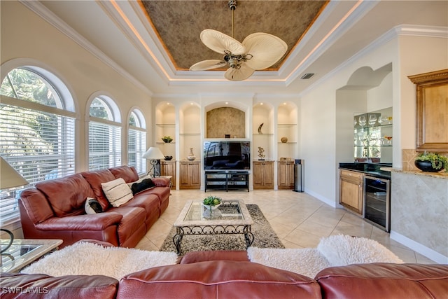 living room featuring light tile patterned floors, built in shelves, a raised ceiling, beverage cooler, and ornamental molding