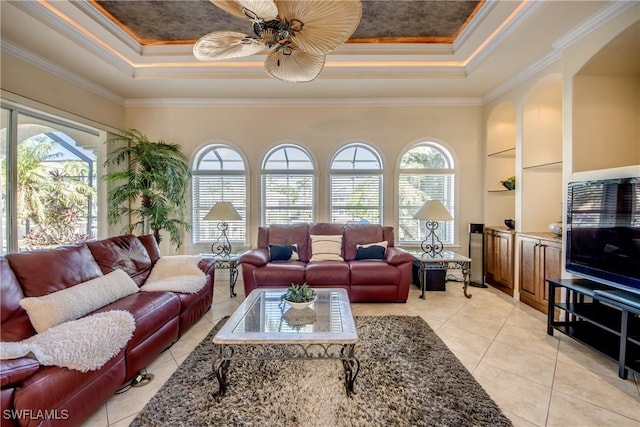 living area featuring a healthy amount of sunlight, light tile patterned floors, a tray ceiling, and ornamental molding