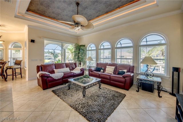 living area with ornamental molding, a ceiling fan, a raised ceiling, and light tile patterned floors