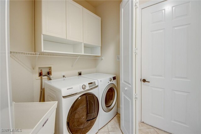 washroom with light tile patterned floors, independent washer and dryer, and cabinets