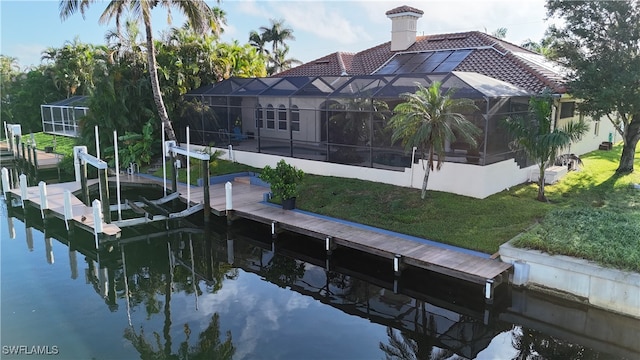 view of dock with a lanai, a lawn, and a water view