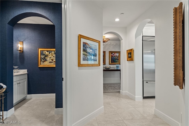 corridor featuring arched walkways, an accent wall, recessed lighting, and baseboards