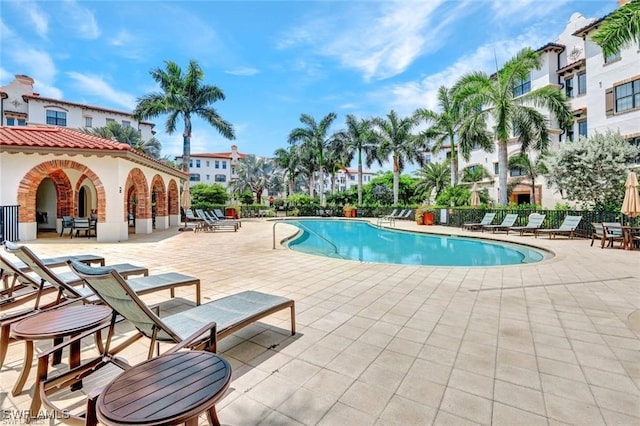 community pool with a patio area and fence