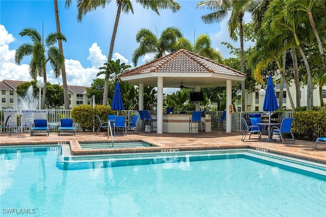 pool with ceiling fan, a patio, a community hot tub, fence, and a gazebo