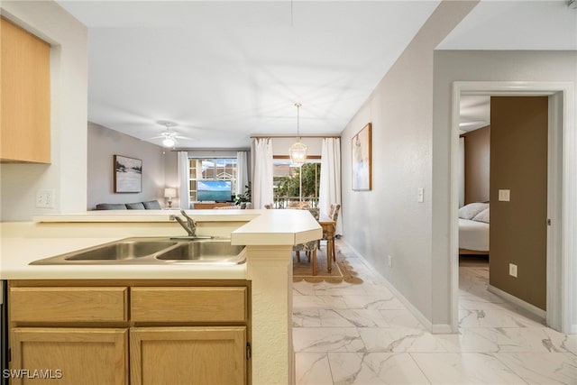 kitchen featuring marble finish floor, light countertops, a sink, a peninsula, and baseboards