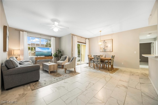 living area with a healthy amount of sunlight, marble finish floor, baseboards, and a ceiling fan