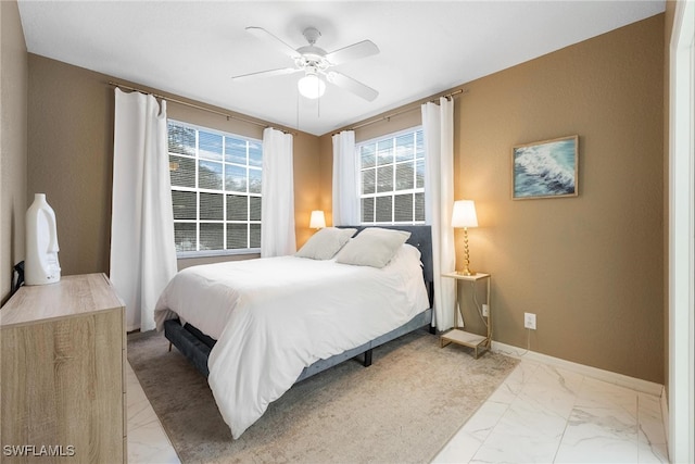 bedroom featuring marble finish floor, multiple windows, ceiling fan, and baseboards