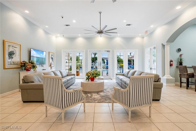 living room featuring arched walkways, crown molding, french doors, ornate columns, and light tile patterned flooring