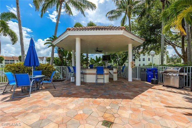 view of patio / terrace with grilling area, fence, outdoor dry bar, and a ceiling fan