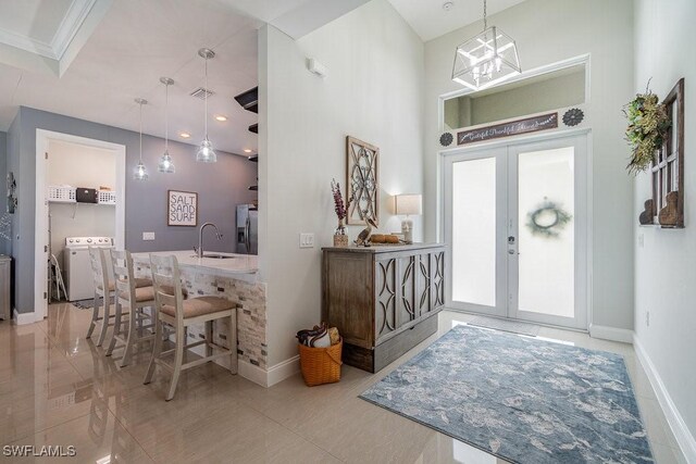 foyer with french doors, ornamental molding, sink, and washing machine and clothes dryer