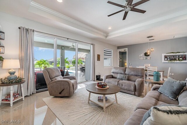 living room featuring light hardwood / wood-style flooring, ceiling fan, a raised ceiling, and crown molding