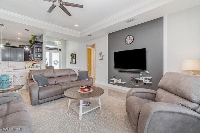 living room featuring ornamental molding, ceiling fan, and sink