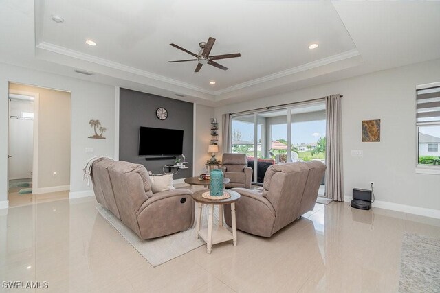 tiled living room with a tray ceiling, ceiling fan, and crown molding