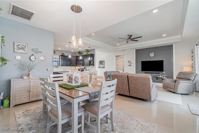 dining area featuring ceiling fan with notable chandelier, a raised ceiling, and ornamental molding