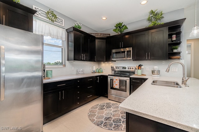 kitchen with pendant lighting, sink, decorative backsplash, appliances with stainless steel finishes, and light stone countertops