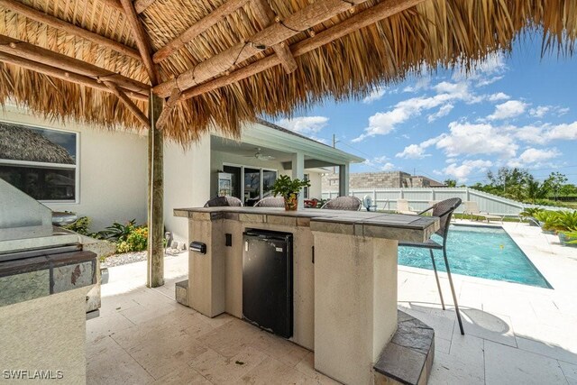 view of patio with a fenced in pool, an outdoor kitchen, and ceiling fan