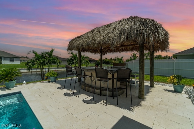 pool at dusk featuring a patio area