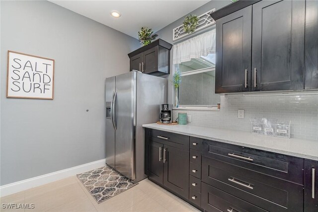 kitchen with stainless steel fridge, light stone countertops, light tile patterned floors, and tasteful backsplash