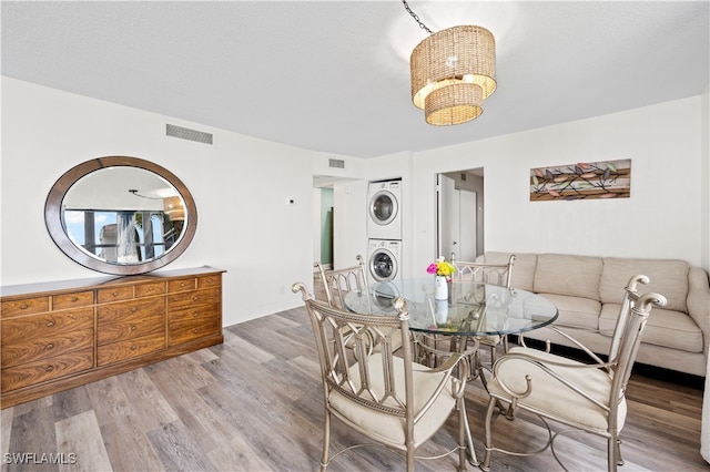 dining area featuring stacked washer and clothes dryer and light hardwood / wood-style floors