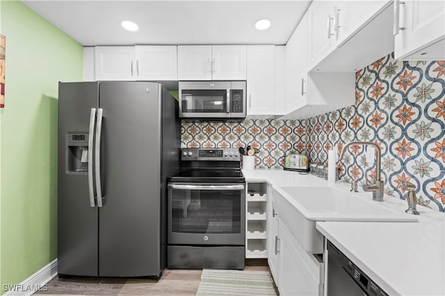 kitchen with stainless steel appliances, decorative backsplash, white cabinetry, and light hardwood / wood-style floors