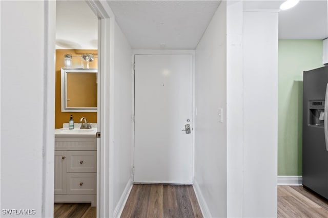 hall with a textured ceiling, sink, and wood-type flooring