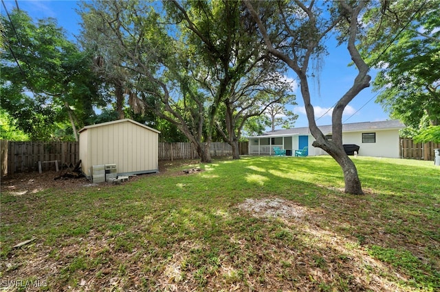 view of yard with an outbuilding, a sunroom, a fenced backyard, and a storage unit