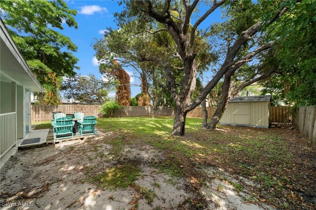 view of yard with a fenced backyard, an outdoor structure, and a storage shed