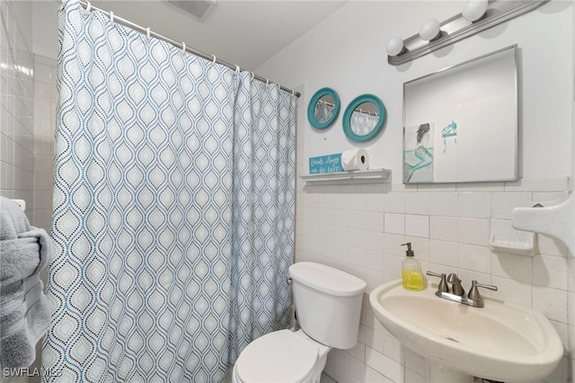 bathroom with tile walls, visible vents, toilet, a sink, and a shower with curtain