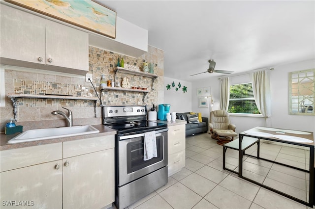 kitchen with light tile patterned floors, a sink, stainless steel electric range, light countertops, and backsplash