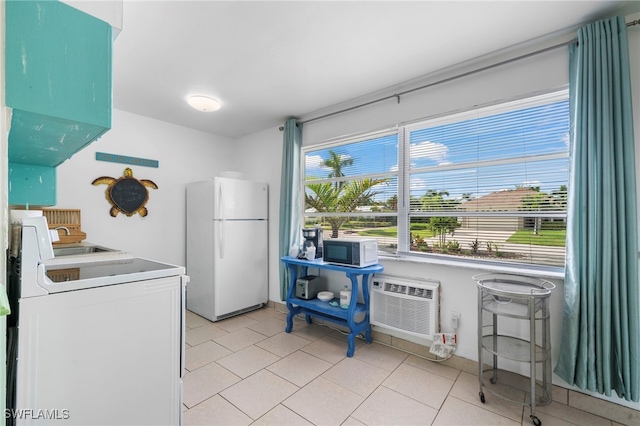 kitchen with a wall unit AC, light tile patterned floors, freestanding refrigerator, a sink, and washer / dryer