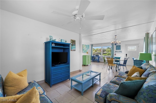 living area featuring baseboards, light tile patterned flooring, and ceiling fan with notable chandelier