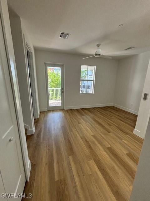 spare room featuring a ceiling fan, wood finished floors, visible vents, and baseboards