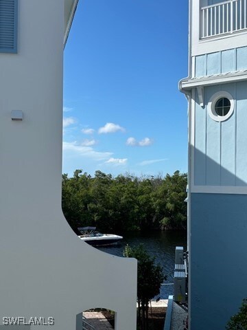 view of property exterior featuring a balcony, a water view, and stucco siding