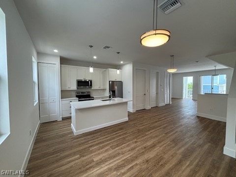 kitchen featuring decorative light fixtures, appliances with stainless steel finishes, dark hardwood / wood-style floors, a center island with sink, and white cabinets